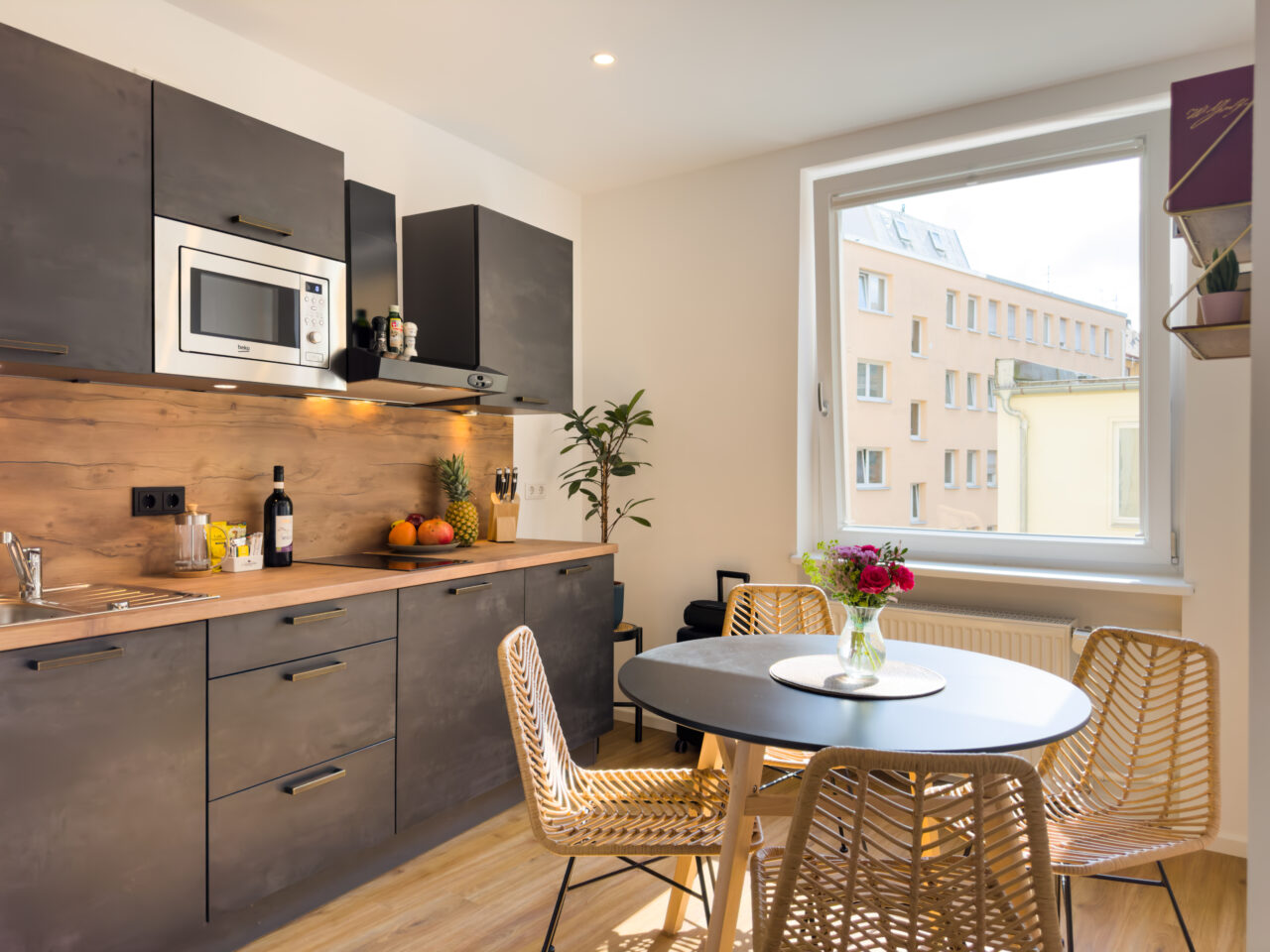 Küchenzeile mit Holzrückwand, Mikrowelle und Rattanstühlen am runden Tisch